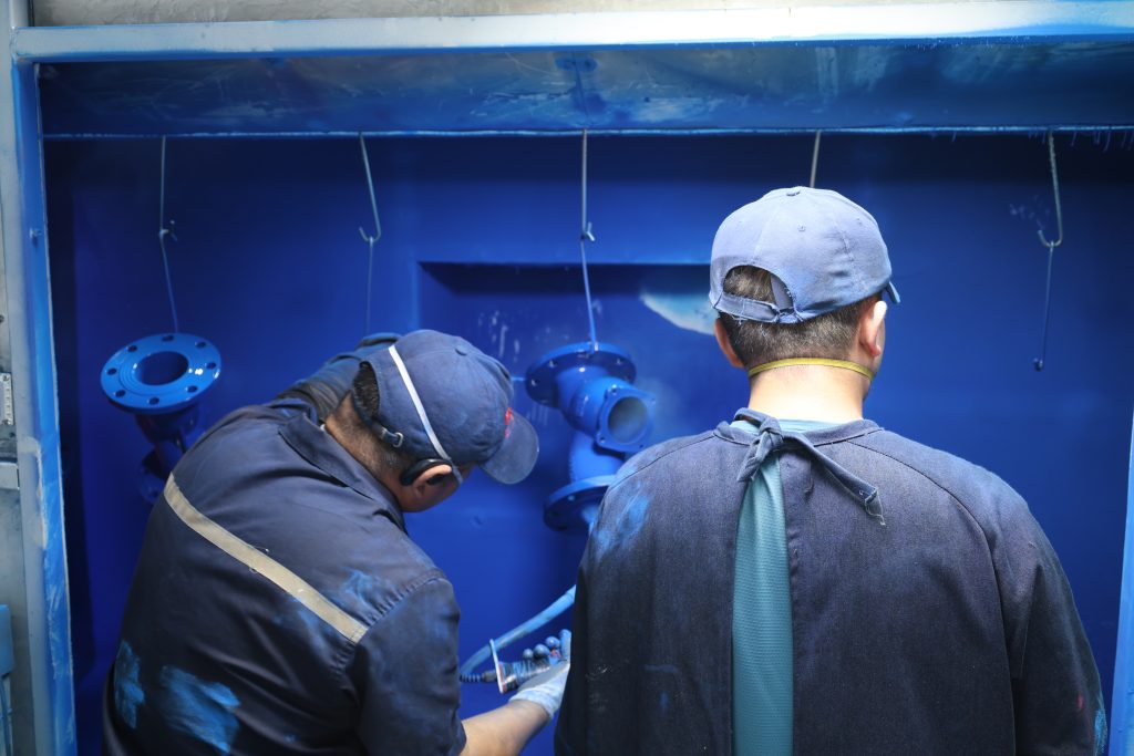 Workers applying fusion bonded epoxy coating inside our valve foundry
